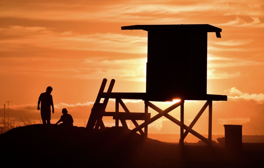 Children play beside a lifeguard tower as sunset approaches at Sunset Beach in Huntington Beach on July 21, 2018. (Frederic J. Brown/AFP via Getty Images)