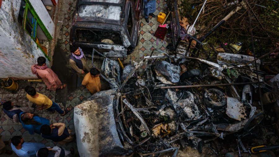 Relatives and neighbors of the Ahmadi family gather around a burned-out vehicle that the family says was hit by a U.S. drone strike, killing 10 people.(Marcus Yam / Los Angeles Times)