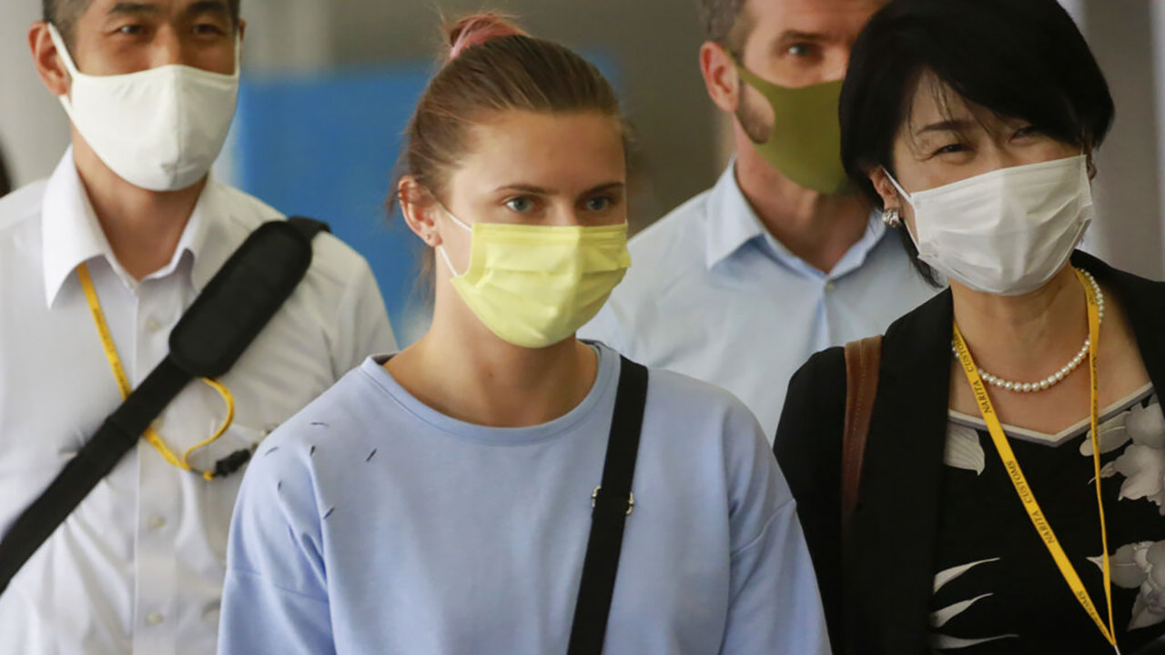 Belarusian Olympic sprinter Krystsina Tsimanouskaya, center, arrives at Narita International Airport in Narita, east of Tokyo Wednesday, Aug. 4, 2021. Tsimanouskaya plans to seek refuge in Europe after accusing team officials of trying to force her to leave the Tokyo Games early. (AP Photo/Koji Sasahara)