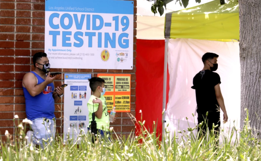 A father waits with his son to be tested for the coronavirus at Northridge Middle School in August 2021.(Genaro Molina / Los Angeles Times)