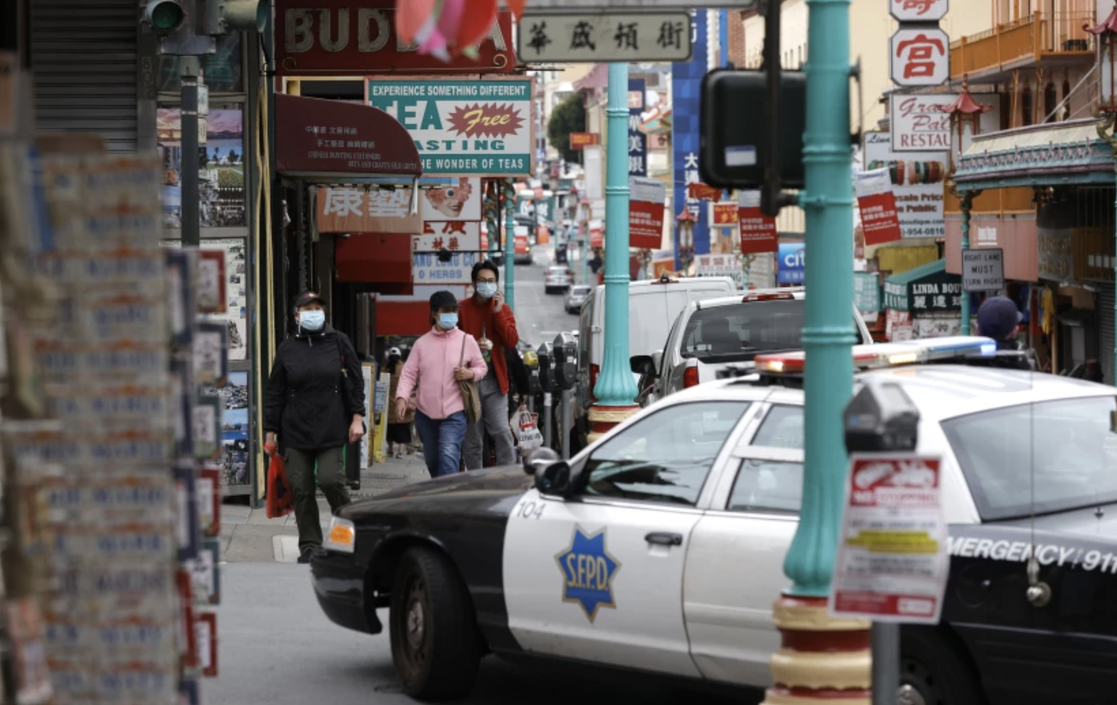 Pedestrians cross the street near a San Francisco police car in Chinatown on March 17. San Francisco is planning disciplinary actions against employees who refused to disclose their COVID-19 vaccination status.(Justin Sullivan / Getty Images)