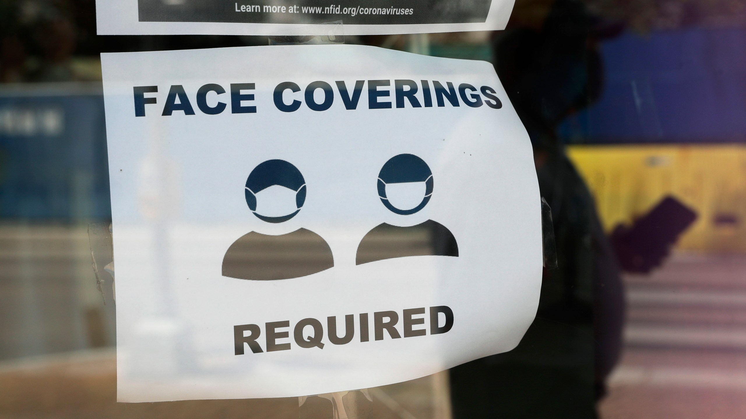 A visitor wearing a mask to protect against the spread of COVID-19 passes a sign requiring masks on July 7, 2020, in San Antonio. Texas. (AP Photo/Eric Gay)