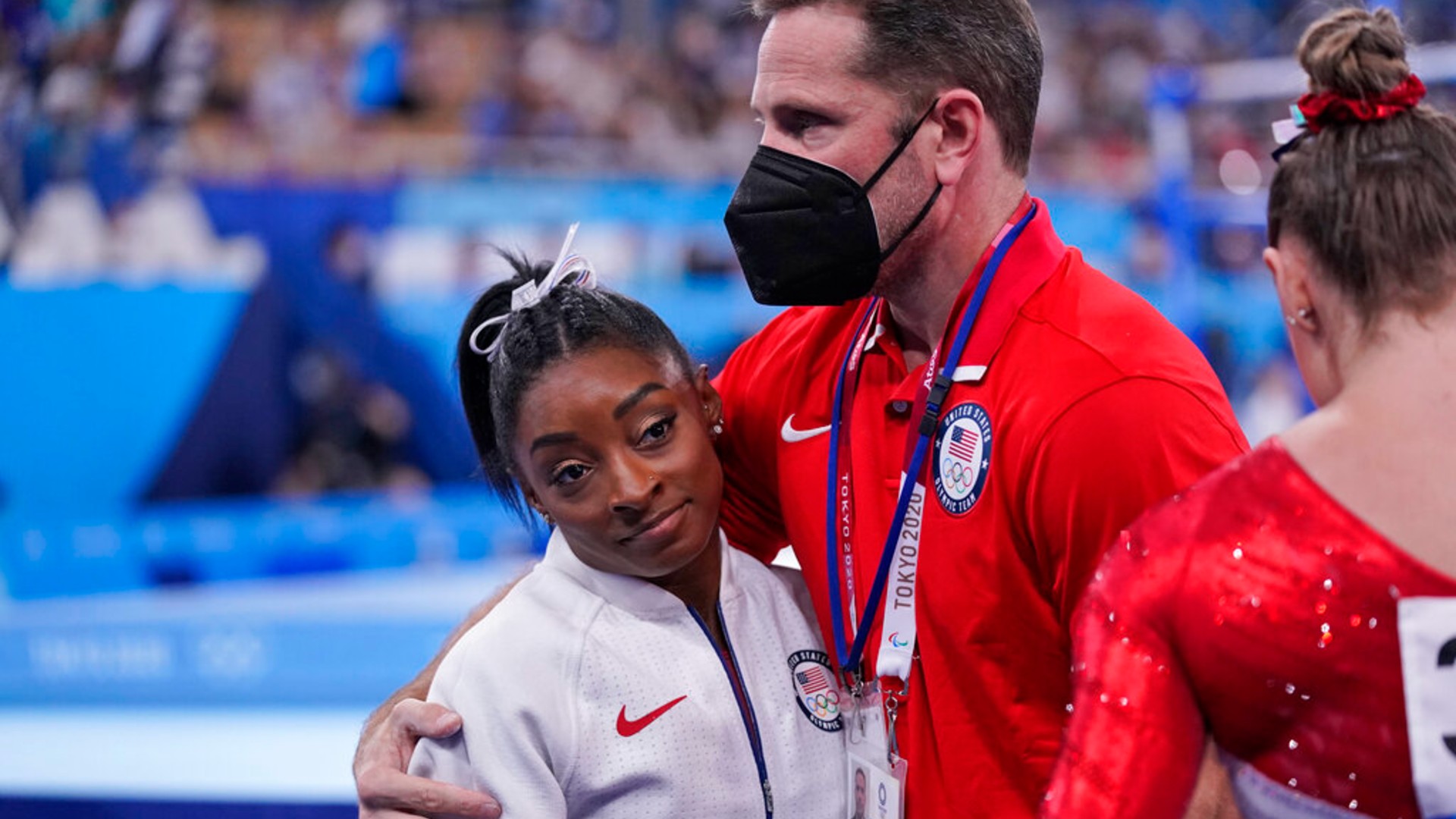 Coach Laurent Landi embraces Simone Biles, after she exited the team final with apparent injury, at the 2020 Summer Olympics, Tuesday, July 27, 2021, in Tokyo. (AP Photo/Gregory Bull)