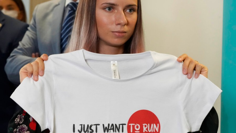 Belarusian Olympic sprinter Krystsina Tsimanouskaya holds up an Olympic-related T-shirt with the slogan "I Just Want to Run" after her news conference in Warsaw, Poland, on Thursday, Aug. 5, 2021. (AP Photo/Czarek Sokolowski)