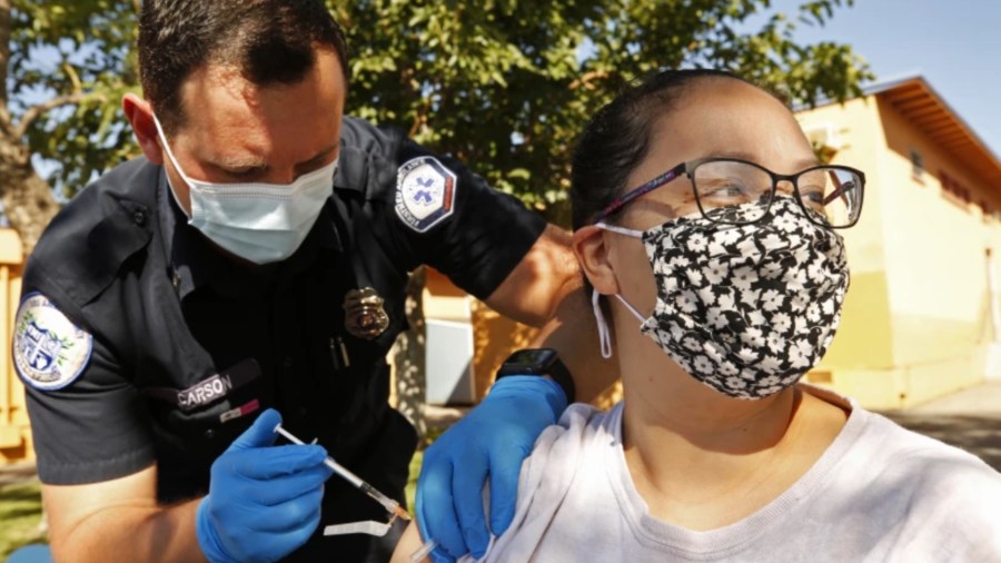 Diana Gomez receives a Pfizer COVID-19 vaccine from Kyle Carson, an EMT with FirstMed Ambulance Services in Arleta.(Al Seib / Los Angeles Times)