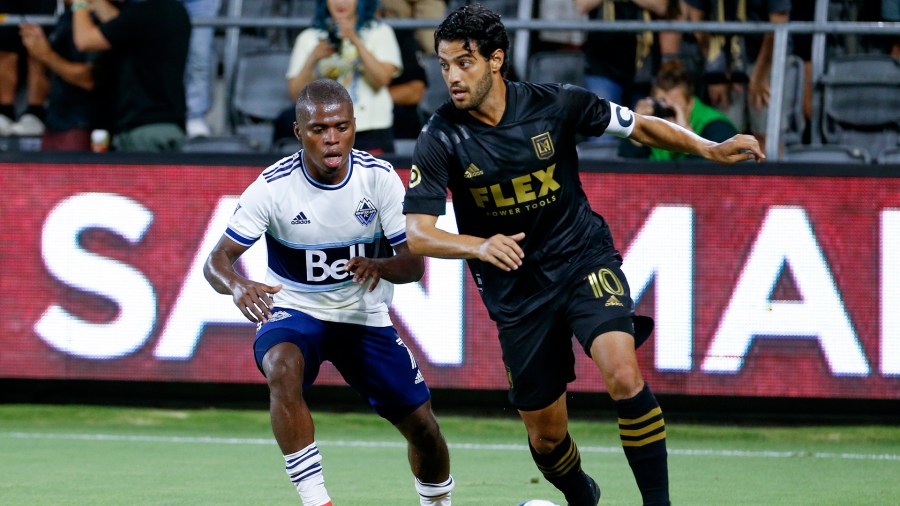 Los Angeles FC forward Carlos Vela drives the ball past Vancouver Whitecaps midfielder Deiber Caicedo during the second half of an MLS soccer match in Los Angeles on July 24, 2021. (Ringo H.W. Chiu/Associated Press)