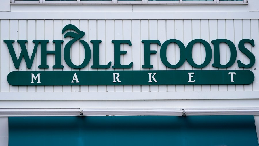 The Whole Foods Market logo is shown on the front of a store, Wednesday, July 14, 2021, in Cambridge, Mass. Amazon, which owns the grocery chain, said Wednesday, Sept. 8, that it will bring its cashier-less technology to two Whole Foods stores for the first time, letting shoppers grab what they need and leave without having to open their wallets. (AP Photo/Charles Krupa)