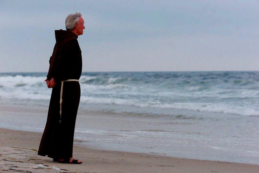 In this July 17, 2000 file photo, Father Mychal Judge, a chaplain with the New York City Fire Department, stands at the shore before a service where 230 candles were lit for the July 17, 1996 victims of TWA Flight 800, at Smith Point Park in Shirley, N.Y. (AP Photo/Ed Betz, File)