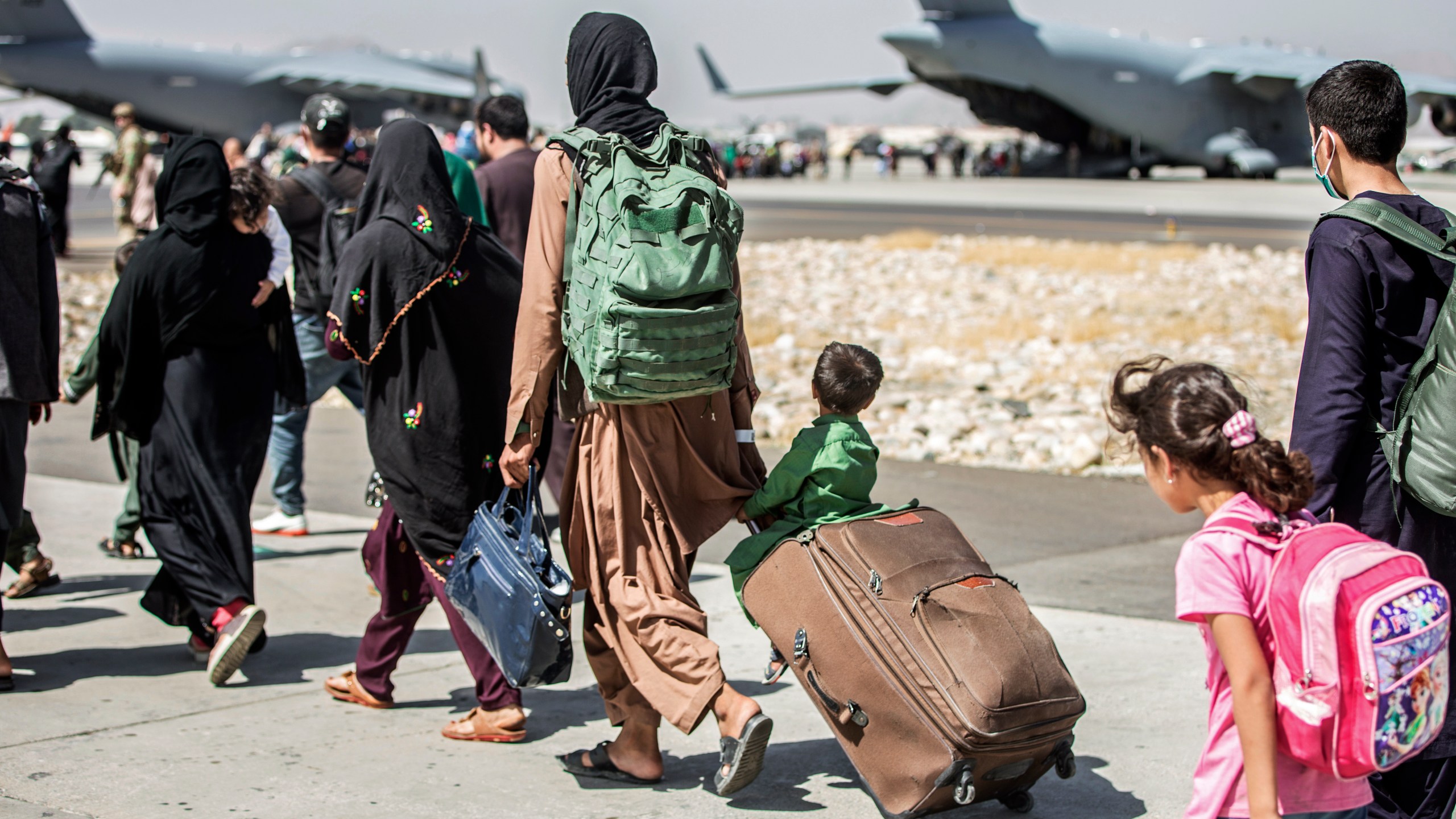 In this Aug. 24, 2021, file photo provided by the U.S. Marine Corps, families walk towards their flight during ongoing evacuations at Hamid Karzai International Airport, in Kabul, Afghanistan. More than 30 California children are stuck in Afghanistan after traveling to the country to see their relatives weeks before the Taliban seized power and US forces left, according to school districts where the kids are enrolled. (Sgt. Samuel Ruiz/U.S. Marine Corps via AP, File)