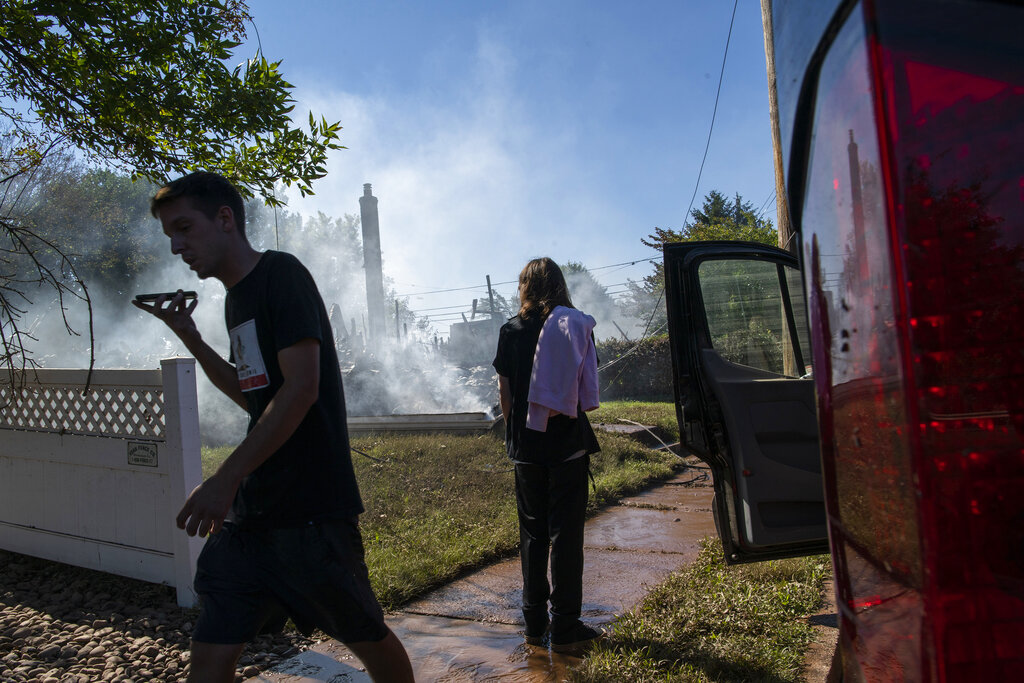 Jason Marotta, right, speaks on his phone as his brother watches the remains of their house that was destroyed due to severe flooding from Tropical Storm Ida in Manville, NJ., Friday, Sept. 3, 2021. (AP Photo/Eduardo Munoz Alvarez)