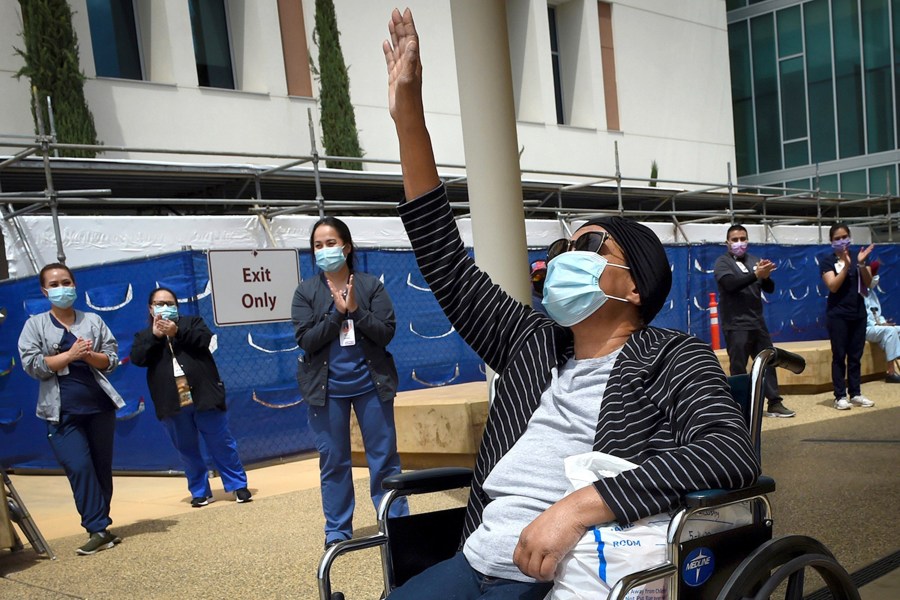 Karen Parker-Bryant, 64, raises a hand skyward after she was released from Clovis Community Hospital in Fresno after a battle with COVID-19 on May 19, 2020. (John Walker / The Fresno Bee via Associated Press)