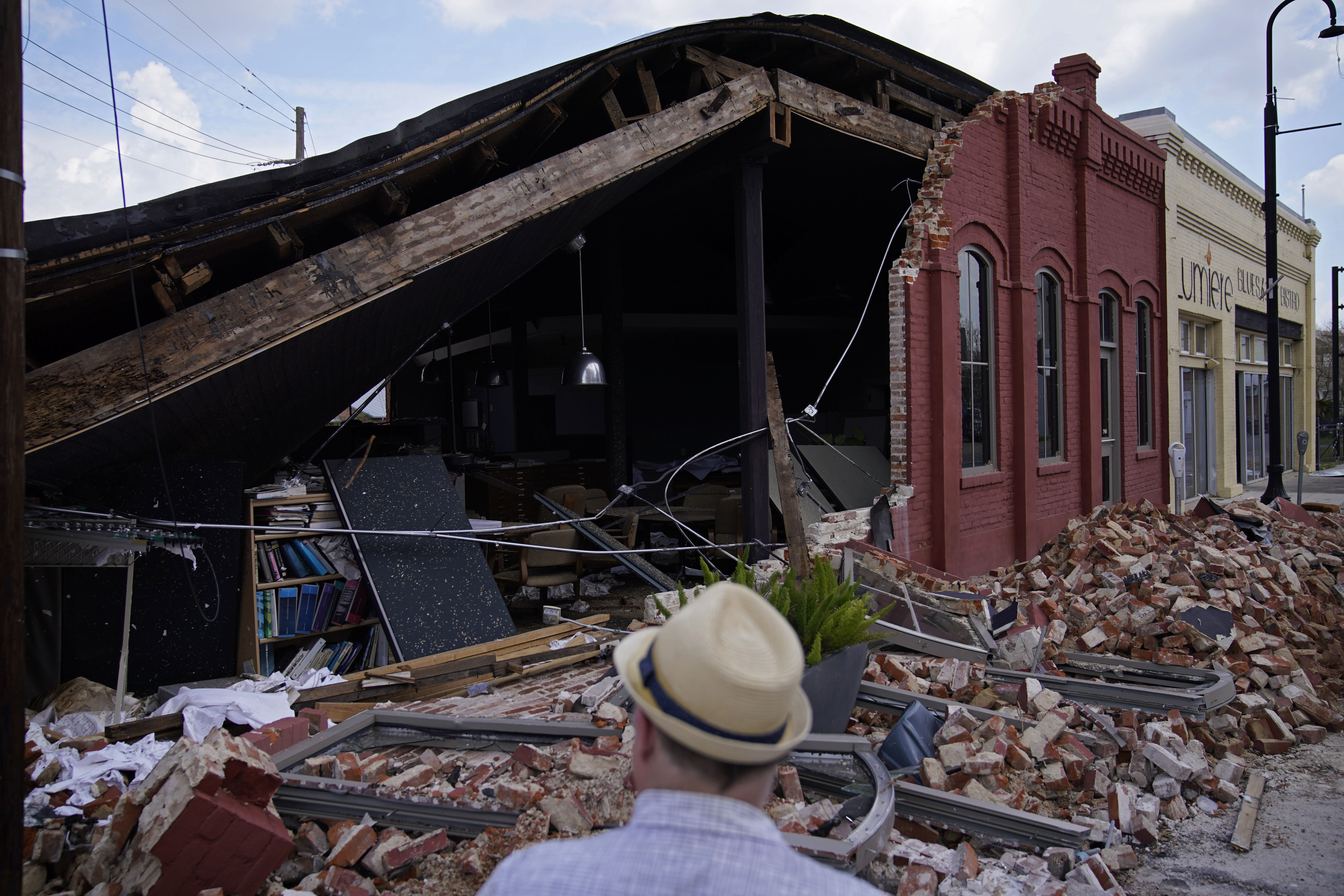 A man looks at a partially collapsed building in the aftermath of Hurricane Ida, Saturday, Sept. 4, 2021, in Houma, La. Full restoration of electricity to some of the hardest-hit areas of Louisiana battered by Hurricane Ida could take until the end of the month, the head of Entergy Louisiana warned Saturday. (AP Photo/John Locher)