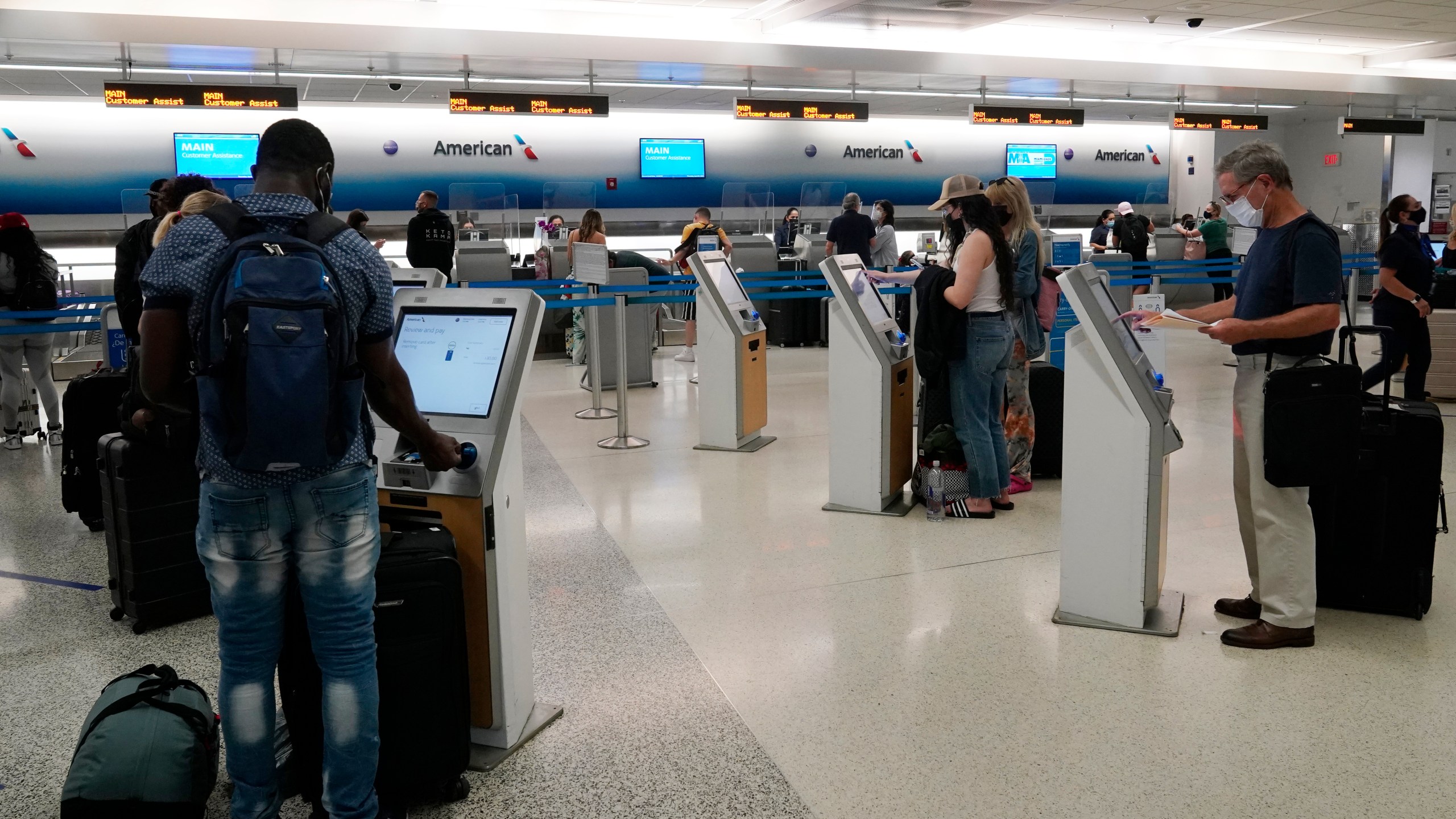 In this April 29, 2021 photo, travelers use the self-service kiosk to check in and pay for luggage at the American Airlines terminal in Miami. The Transportation Department is detailing efforts it's making to help airline customers who didn't get refunds after their flights were canceled during the early days of the pandemic last year. The department says, Friday, Sept. 10, in a new report that it investigated 20 airlines over failures to issue prompt refunds to customers, and 18 of those probes are still going on.(AP Photo/Marta Lavandier)