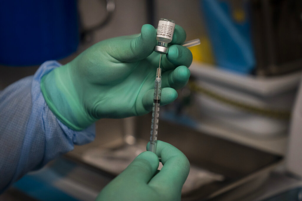 In this Aug. 26, 2021 file photo, Parsia Jahanbani prepares a syringe with the Pfizer COVID-19 vaccine in a mobile vaccine clinic operated by Families Together of Orange County in Santa Ana, California. (AP Photo/Jae C. Hong, File)