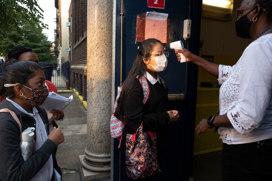 A girl has her temperature checked as she arrives for the first day of school at Brooklyn's PS 245 elementary school on Sept. 13, 2021, in New York. (Mark Lennihan/Associated Press)