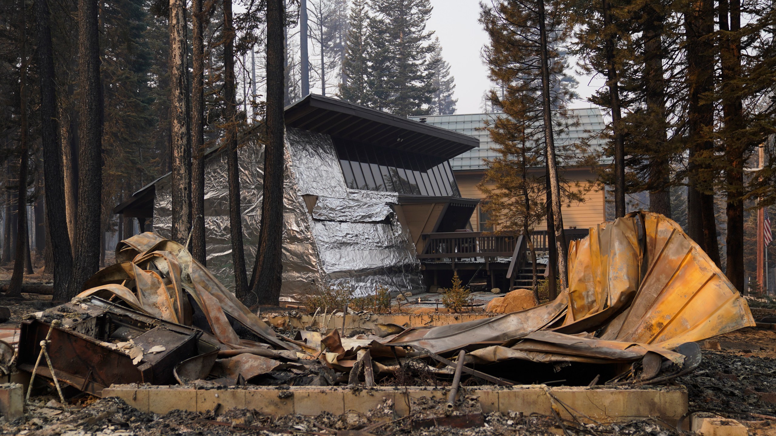 In this Sept. 2, 2021 file photo a cabin partially covered in fire-resistant material stands behind a property destroyed in the Caldor Fire in Twin Bridges, Calif. (AP Photo/Jae C. Hong,File)