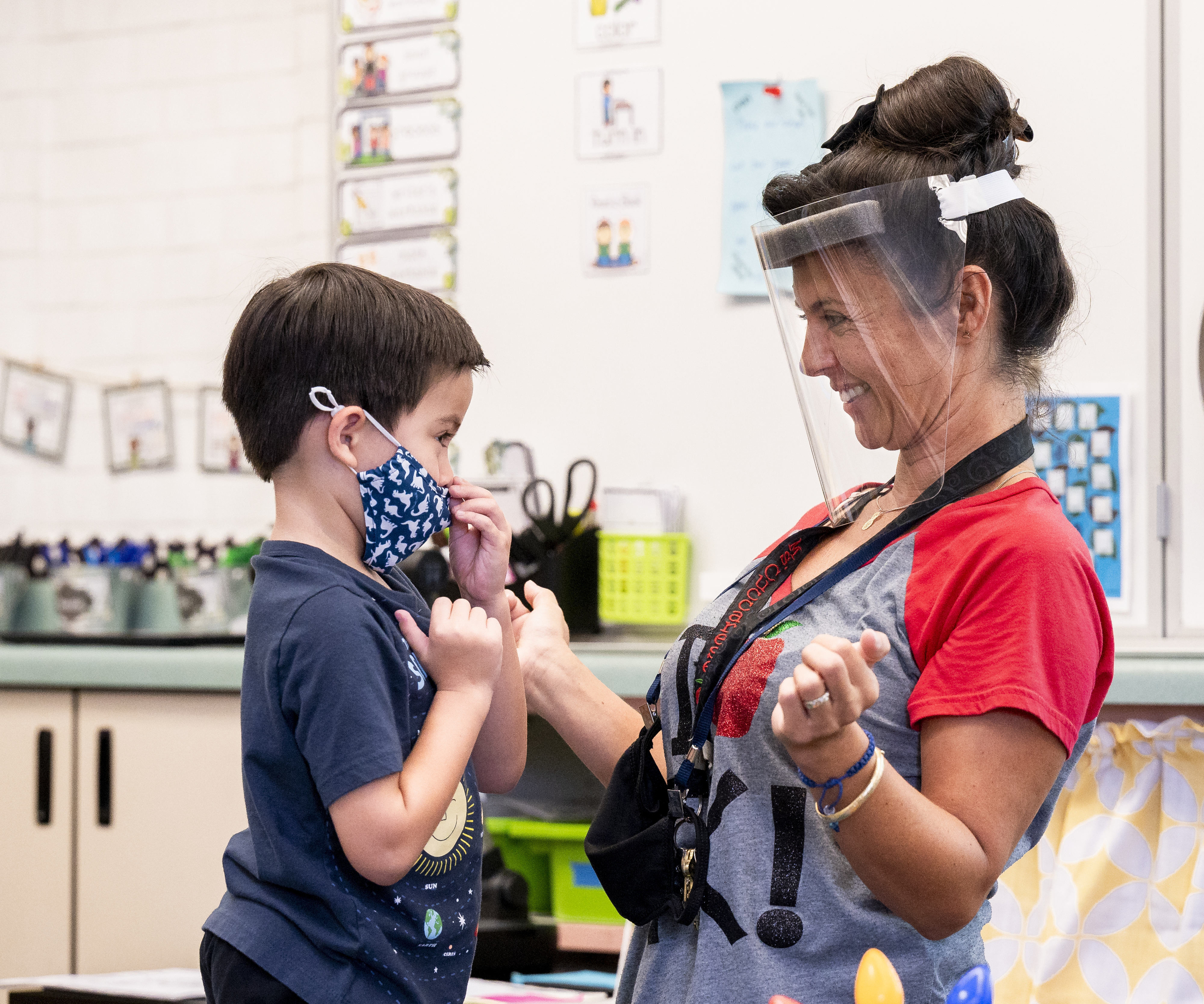 In this Aug. 12, 2021, file photo, a student gets help with his mask from transitional kindergarten teacher Annette Cuccarese during the first day of classes at Tustin Ranch Elementary School in Tustin, Calif. Now that California schools have welcomed students back to in-person learning, they face a new challenge: A shortage of teachers and all other staff, the likes of which some districts say they've never seen. (Paul Bersebach/The Orange County Register via AP, File)