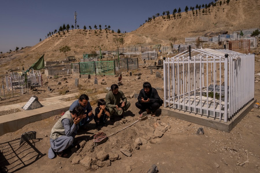 In this Monday, Sept. 13, 2021 file photo, the Ahmadi family pray at the cemetery next to family graves of family members killed by a US drone strike, in Kabul, Afghanistan. (AP Photo/Bernat Armangue, File)