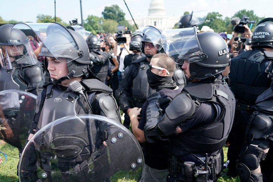 Police circle a man, center with glasses, during a rally near the U.S. Capitol in Washington, Saturday, Sept. 18, 2021. The rally was planned by allies of former President Donald Trump and aimed at supporting the so-called "political prisoners" of the Jan. 6 insurrection at the U.S. Capitol. (AP Photo/Gemunu Amarasinghe)