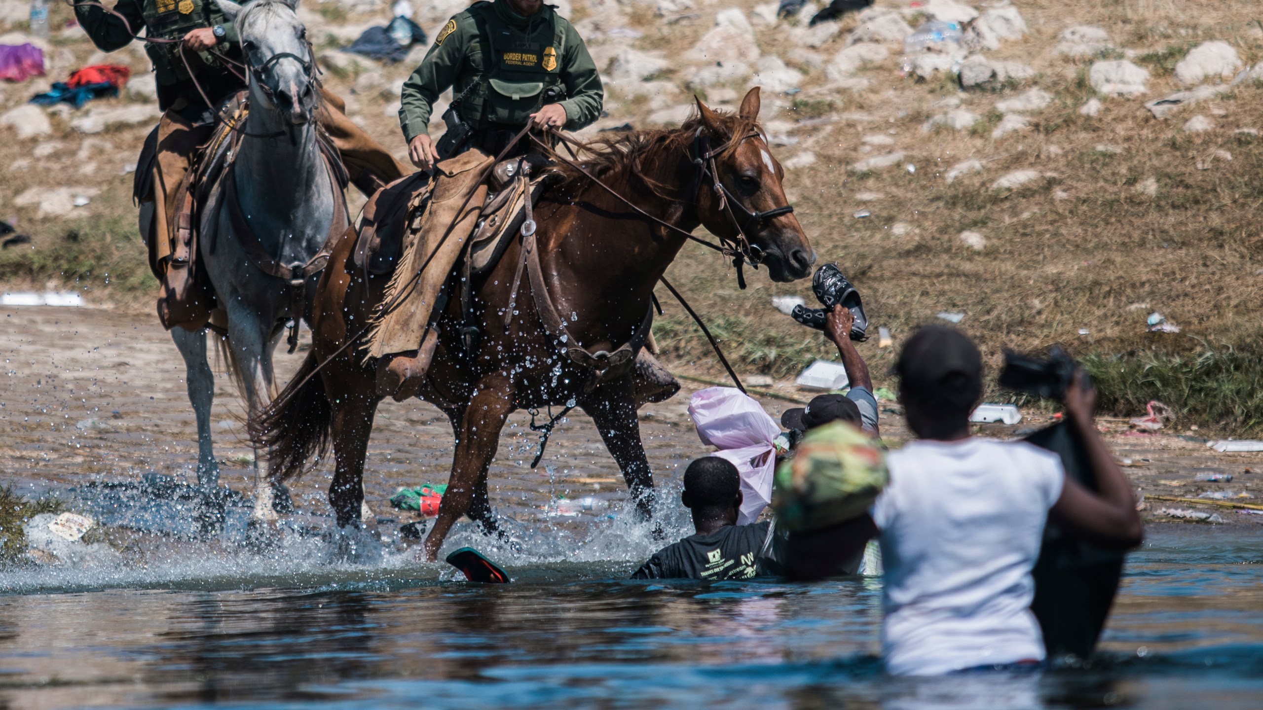 U.S. Customs and Border Protection mounted officers attempt to contain migrants as they cross the Rio Grande from Ciudad Acuña, Mexico, into Del Rio, Texas, Sunday, Sept. 19, 2021. Thousands of Haitian migrants have been arriving to Del Rio, Texas, as authorities attempt to close the border to stop the flow of migrants. (AP Photo/Felix Marquez)