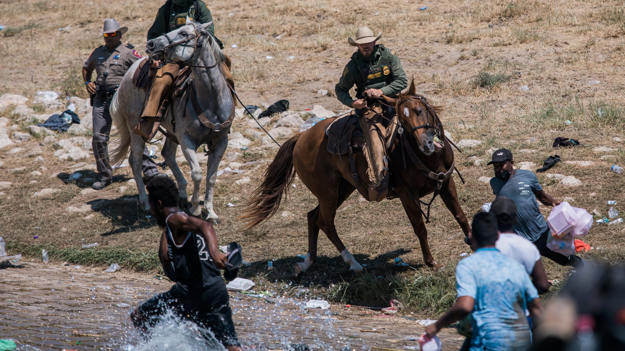 U.S. Customs and Border Protection mounted officers attempt to contain migrants as they cross the Rio Grande from Ciudad Acuña, Mexico, into Del Rio, Texas, Sunday, Sept. 19, 2021. (AP Photo/Felix Marquez)