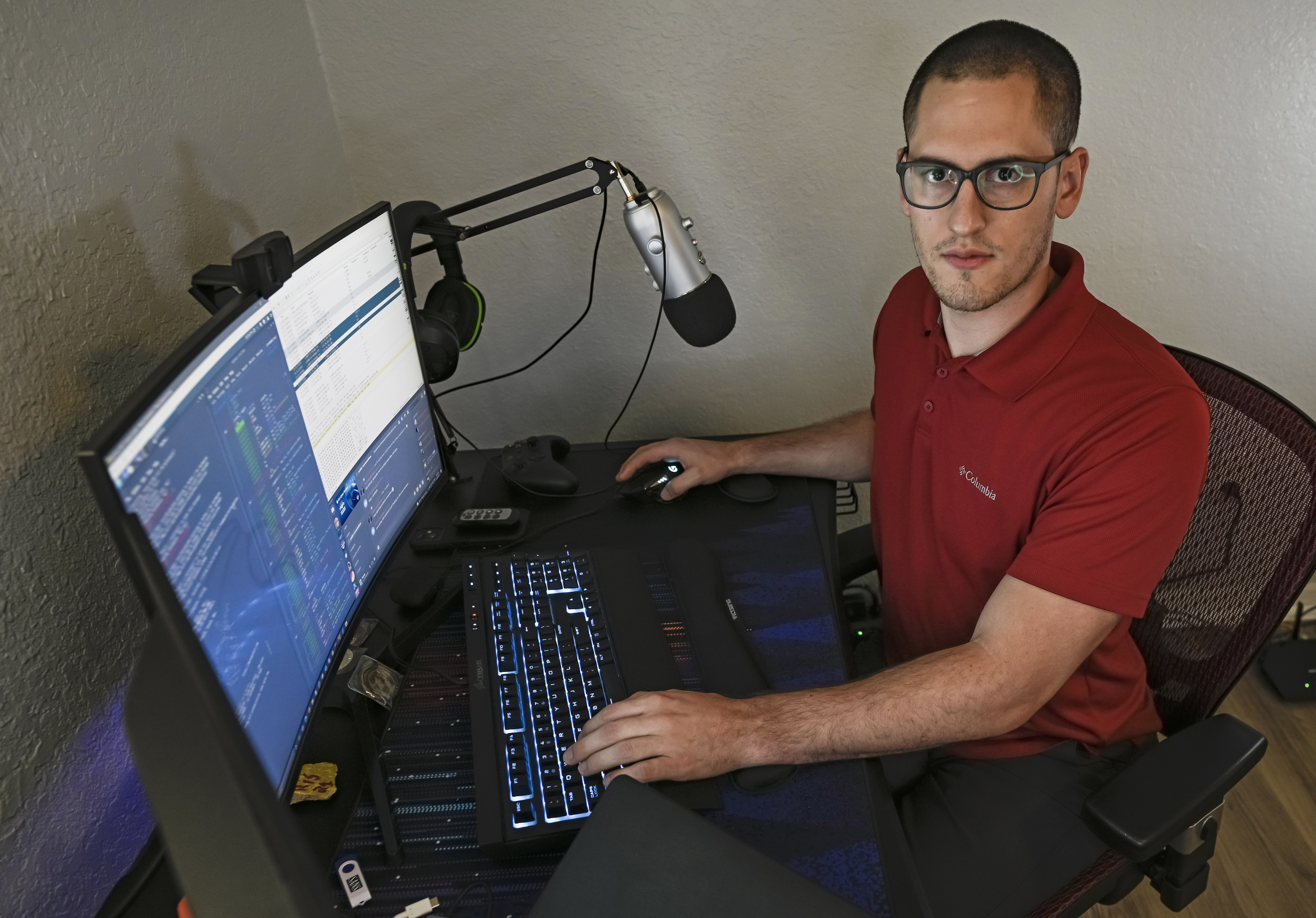 In this Sept. 20, 2021, photo Austin Moody poses for a photo as he sits a his home work station in Tampa, Fla. Moody, the Michigan native, got a scholarship from the Department of Defense that required working for the agency at least a year after graduating. (AP Photo/Steve Nesius)