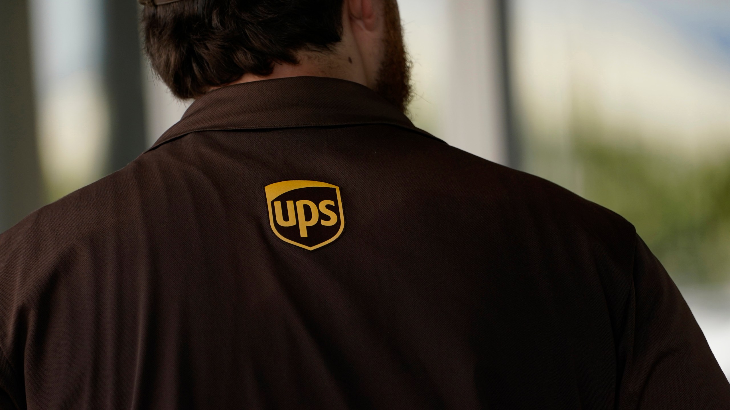 A UPS logo is on the shirt of a driver as he enters a United Parcel Service store with packages in Jackson, Miss., Monday, July 26, 2021. Amazon, Chobani, UPS and more than 30 other companies have vowed to hire and train refugees fleeing Afghanistan for the U.S. The companies said Tuesday, Sept. 21, that they want to help the tens of thousands of Afghan refugees coming to America to integrate into the economy. (AP Photo/Rogelio V. Solis, File)