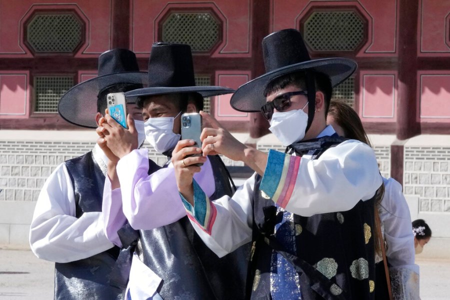 Men wearing face masks as a precaution against the coronavirus take photos as they visit to celebrate Chuseok holidays, the Korean version of Thanksgiving Day, at the Gyeongbok Palace in Seoul, South Korea, Wednesday, Sept. 22, 2021. (AP Photo/Ahn Young-joon)