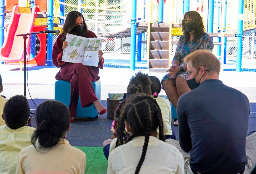 Meghan, the Duchess of Sussex, reads from her book "The Bench," as Prince Harry, the Duke of Sussex, foreground right, and second grade students listen, during their visit to P.S. 123, the Mahalia Jackson School, in New York's Harlem neighborhood on Sept. 24, 2021. (AP Photo/Richard Drew)