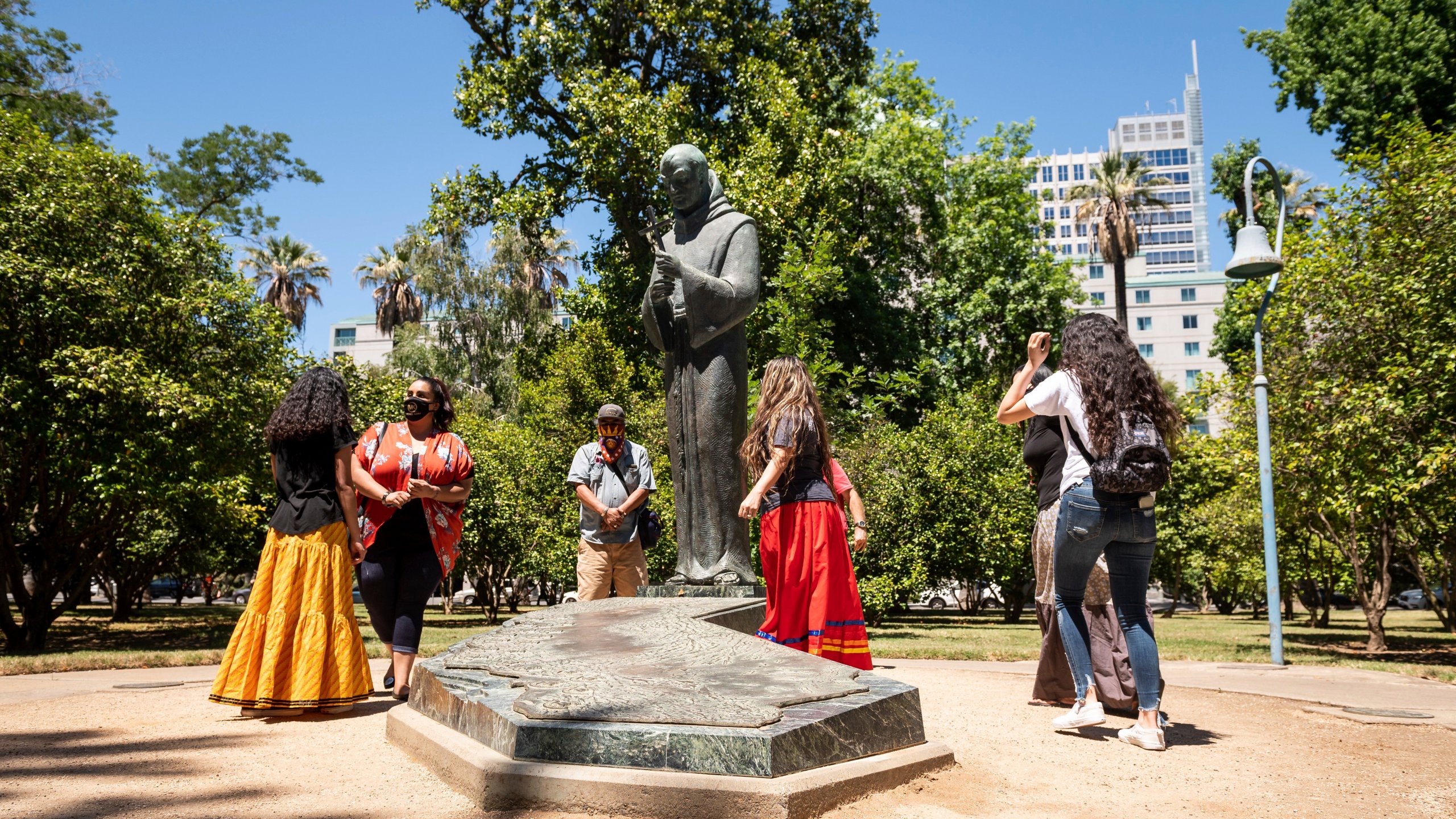 In this June 16, 2020, photo, people gather near the Father Junipero Serra statue on the Capitol Park grounds in Sacramento, Calif. (Xavier Mascarenas/The Sacramento Bee via Associated Press)