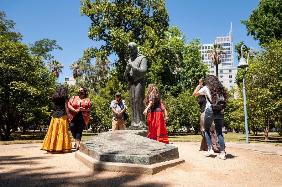 In this June 16, 2020, photo, people gather near the Father Junipero Serra statue on the Capitol Park grounds in Sacramento, Calif. (Xavier Mascarenas/The Sacramento Bee via Associated Press)