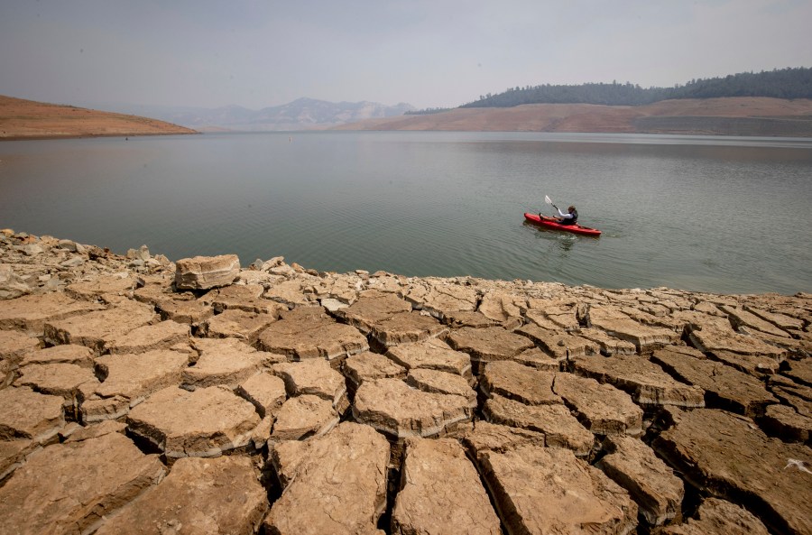 A kayaker fishes in Lake Oroville as water levels remain low due to continuing drought conditions on Aug. 22, 2021. (Ethan Swope / Associated Press)