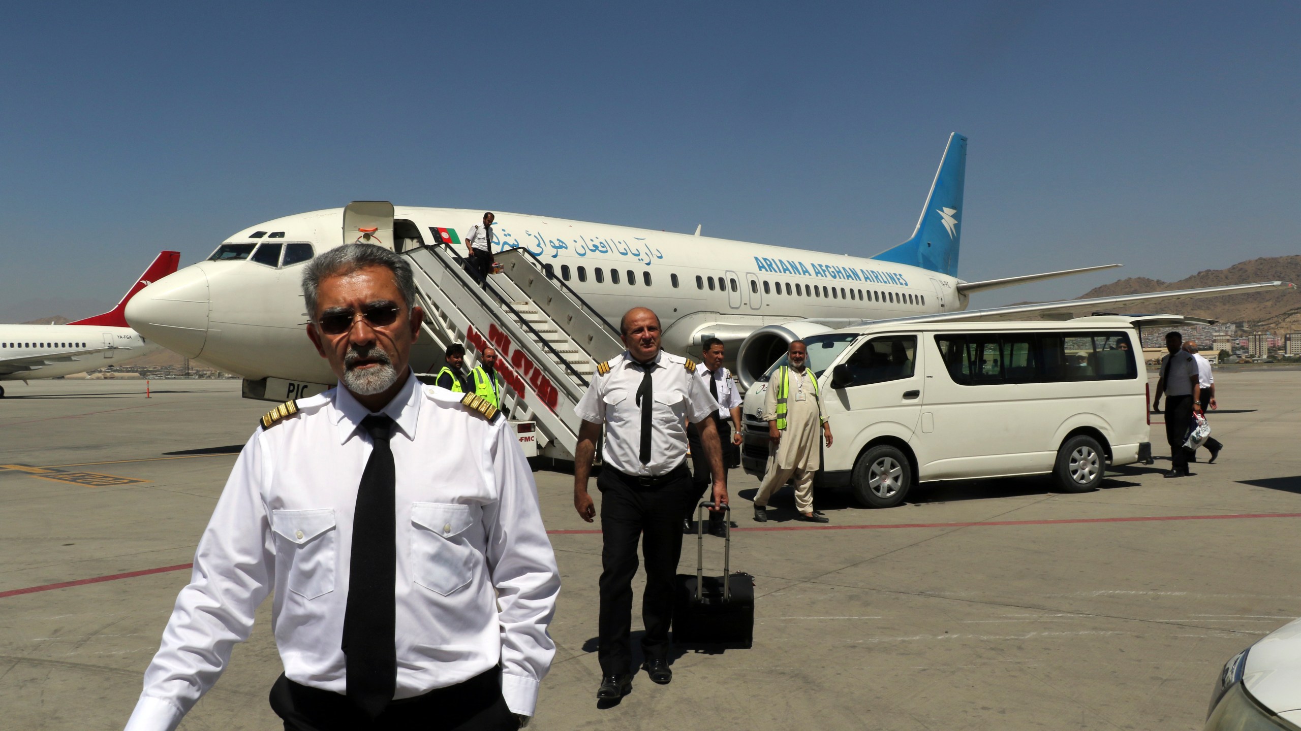 Pilots of Ariana Afghan Airlines walk on the tarmac after landing at Hamid Karzai International Airport in Kabul, Afghanistan, Sunday, Sept. 5, 2021. Some domestic flights have resumed at Kabul's airport, with the state-run Ariana Afghan Airlines operating flights to three provinces. (AP Photo/Wali Sabawoon)