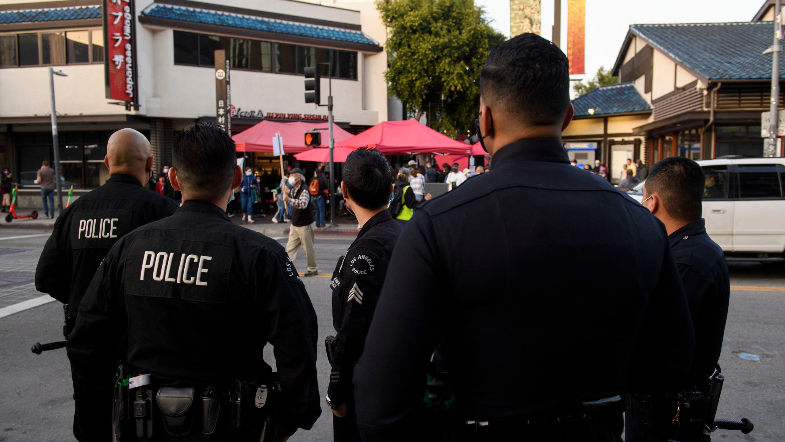 Los Angeles Police Department (LAPD) officers watch as a memorial procession for nursing home residents who died due to Covid-19 proceeds on March 20, 2021, in the Little Tokyo neighborhood of Los Angeles. (PATRICK T. FALLON/AFP via Getty Images)