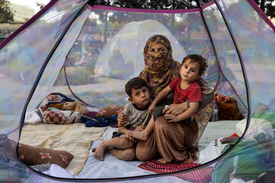 Farzia, 28, who lost her husband in Baghlan one week ago to fighting by the Taliban sits with her children, Subhan, 5, and Ismael ,2, in a tent at a makeshift IDP camp in Share-e-Naw park to various mosques and schools on August 12, 2021 in Kabul, Afghanistan. (Paula Bronstein/Getty Images)