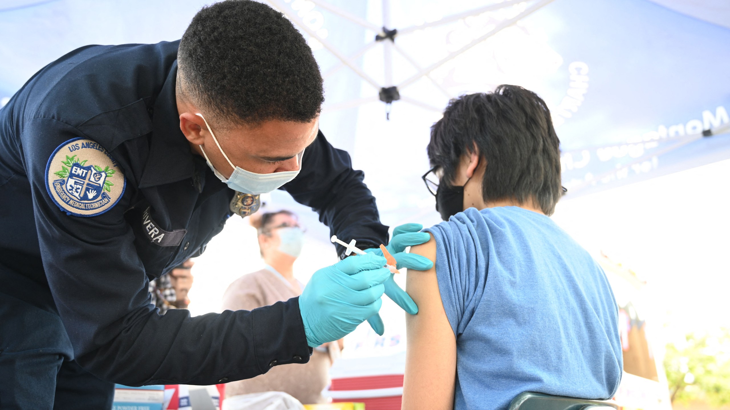 Brandon Rivera, a Los Angeles County emergency medical technician, gives a second does of Pfizer-BioNTech COVID-19 vaccine to Aaron Delgado, 16, at a pop up vaccine clinic in the Arleta neighborhood of Los Angeles on Aug. 23, 2021. (ROBYN BECK/AFP via Getty Images)