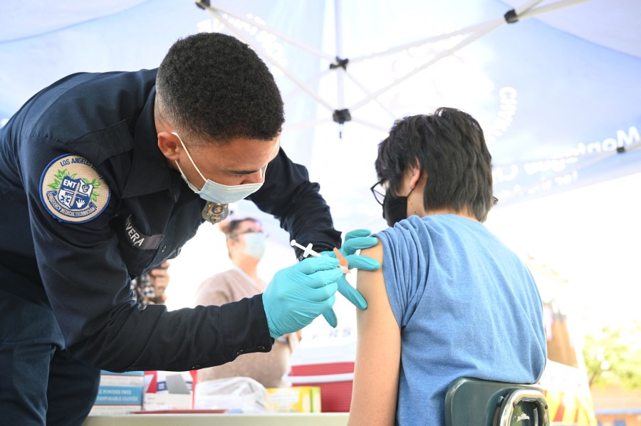 Brandon Rivera, a Los Angeles County emergency medical technician, gives a second does of Pfizer-BioNTech COVID-19 vaccine to Aaron Delgado, 16, at a pop up vaccine clinic in the Arleta neighborhood of Los Angeles on Aug. 23, 2021. (ROBYN BECK/AFP via Getty Images)