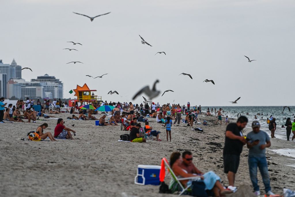 People sit on the sand in Miami Beach, Florida, on September 6, 2021, during the Labor Day holiday. (CHANDAN KHANNA/AFP via Getty Images)