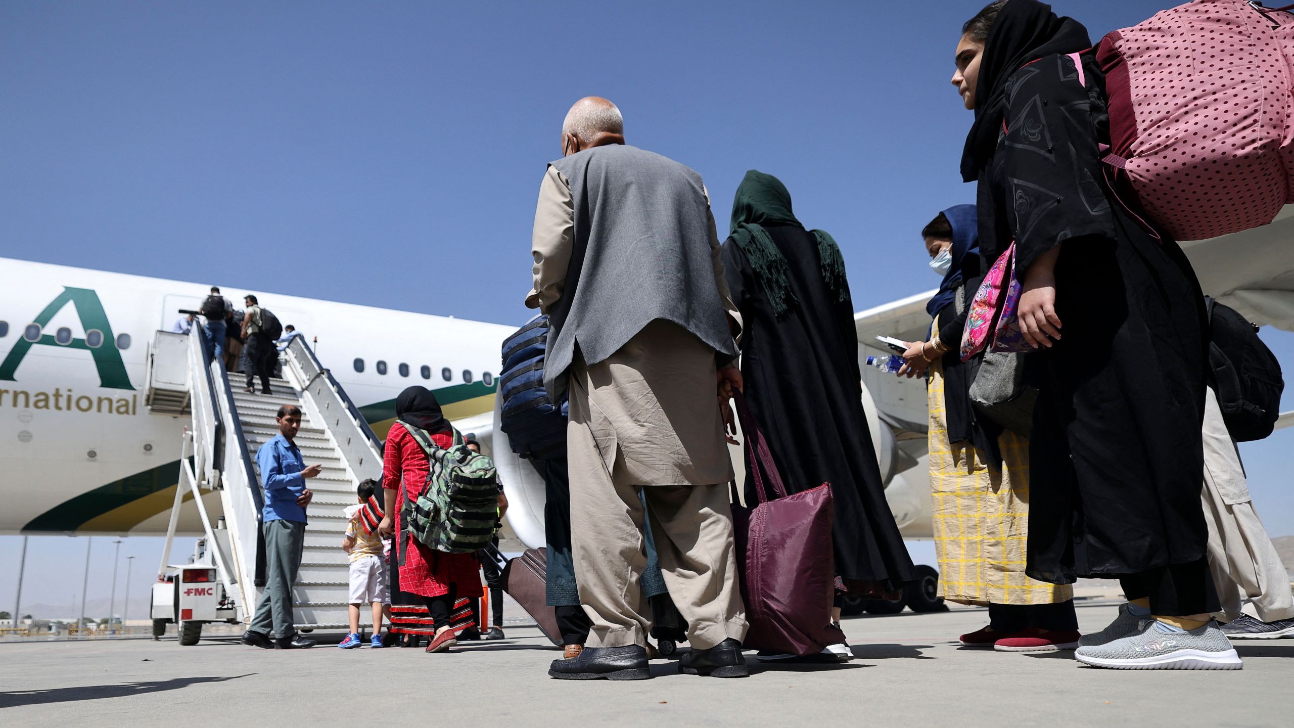 Passengers stand in a queue to board a Pakistan International Airlines plane, the first international commercial flight to land since the Taliban retook power in Afghanistan, at the airport in Kabul on Sept. 13, 2021. (Karim Sahib / AFP / Getty Images)