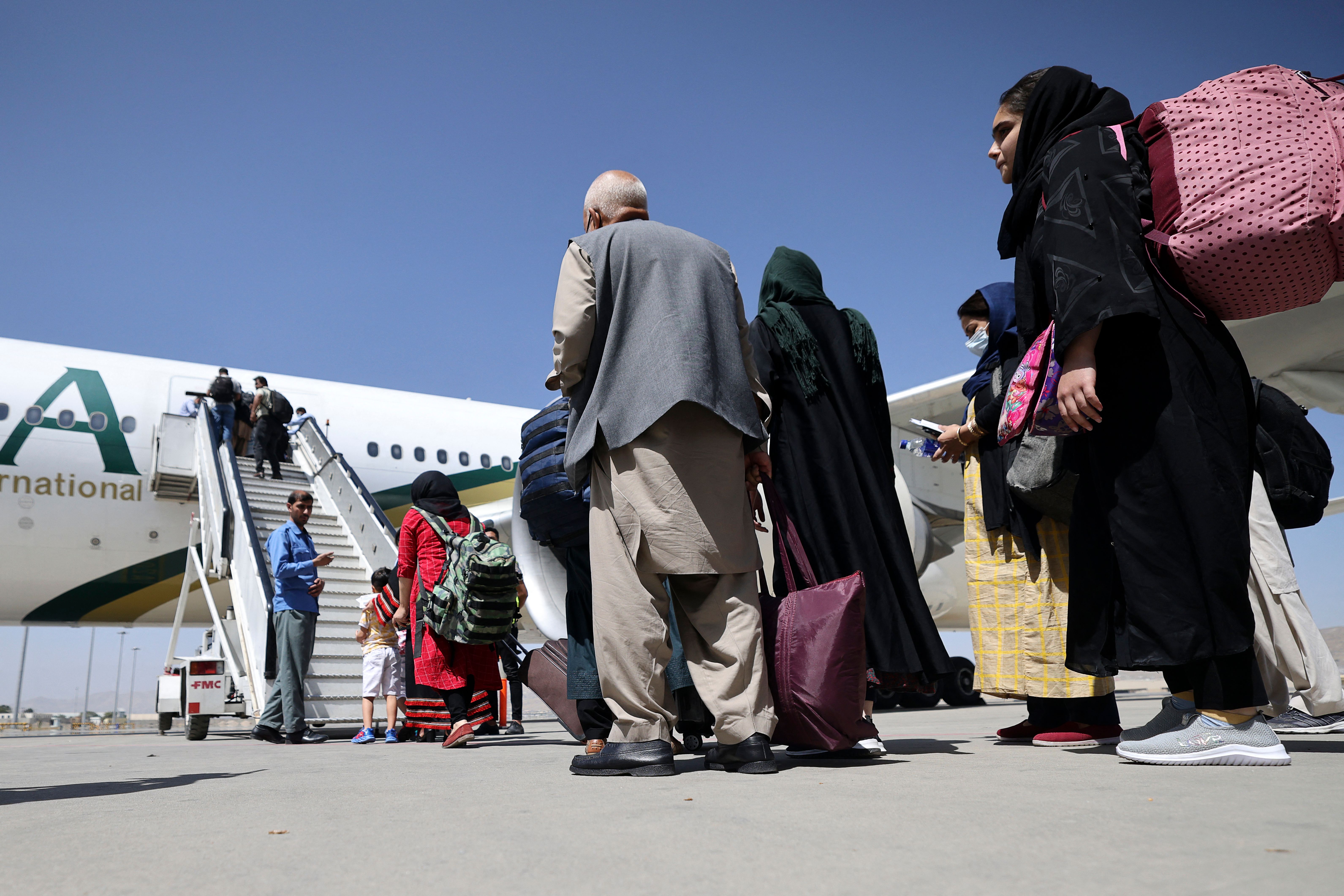 Passengers stand in a queue to board a Pakistan International Airlines plane, the first international commercial flight to land since the Taliban retook power in Afghanistan, at the airport in Kabul on Sept. 13, 2021. (Karim Sahib / AFP / Getty Images)