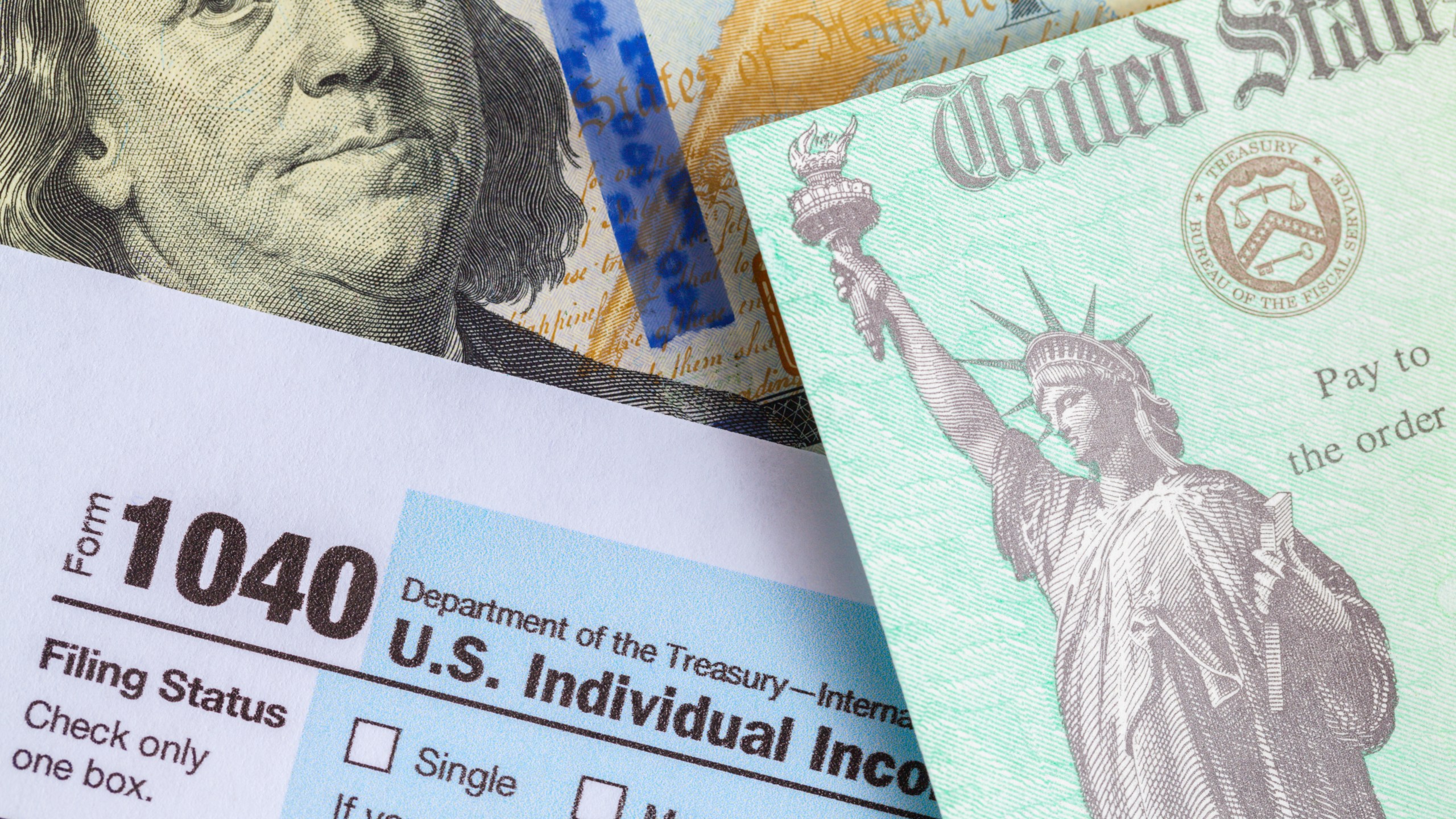 A tax refund check is seen on top of Form 1040 and a $100 bill. (iStock/Getty Images Plus)