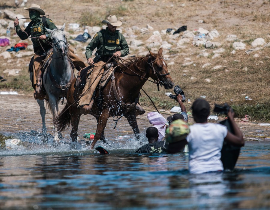 U.S. Customs and Border Protection mounted officers attempt to contain migrants as they cross the Rio Grande from Ciudad Acuña, Mexico, into Del Rio, Texas, Sunday, Sept. 19, 2021. Thousands of Haitian migrants have been arriving to Del Rio, Texas, as authorities attempt to close the border to stop the flow of migrants. (AP Photo/Felix Marquez)