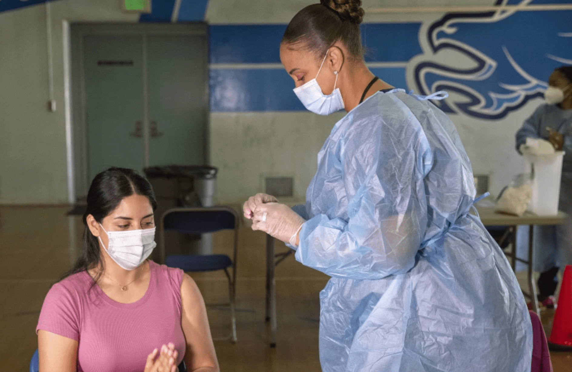 A teacher’s assistant at San Fernando Middle School receives her first dose of the Pfizer vaccine at a clinic inside the school gymnasium. Deadlines are approaching in the Los Angeles school district for employees and students to receive required COVID-19 vaccines. (Mel Melcon / Los Angeles Times)