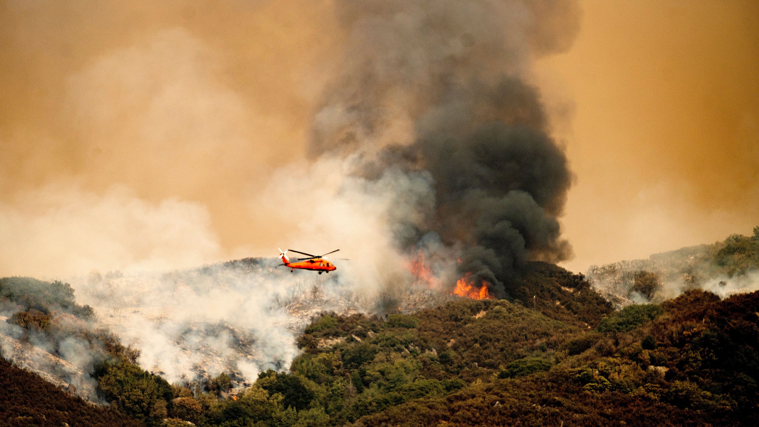 A helicopter prepares to drop water on the KNP Complex Fire in Sequoia National Park, Calif., on Wednesday, Sept. 15, 2021. The blaze is burning near the Giant Forest, home to more than 2,000 giant sequoias. (AP Photo/Noah Berger)