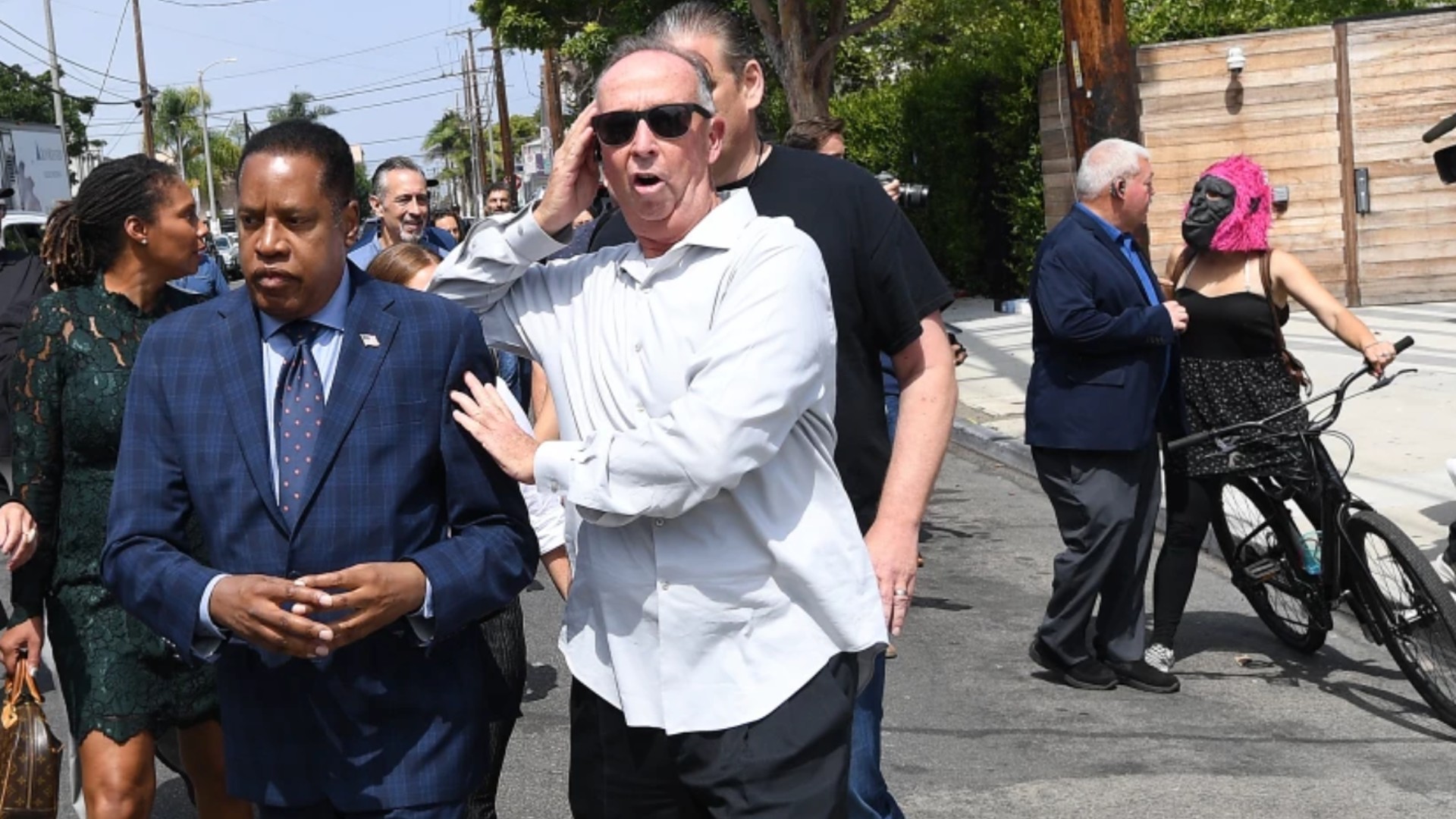 Republican gubernatorial candidate Larry Elder is escorted by a security guard after a woman in a gorilla mask threw an egg in the candidate’s direction.(Wally Skalij/Los Angeles Times)