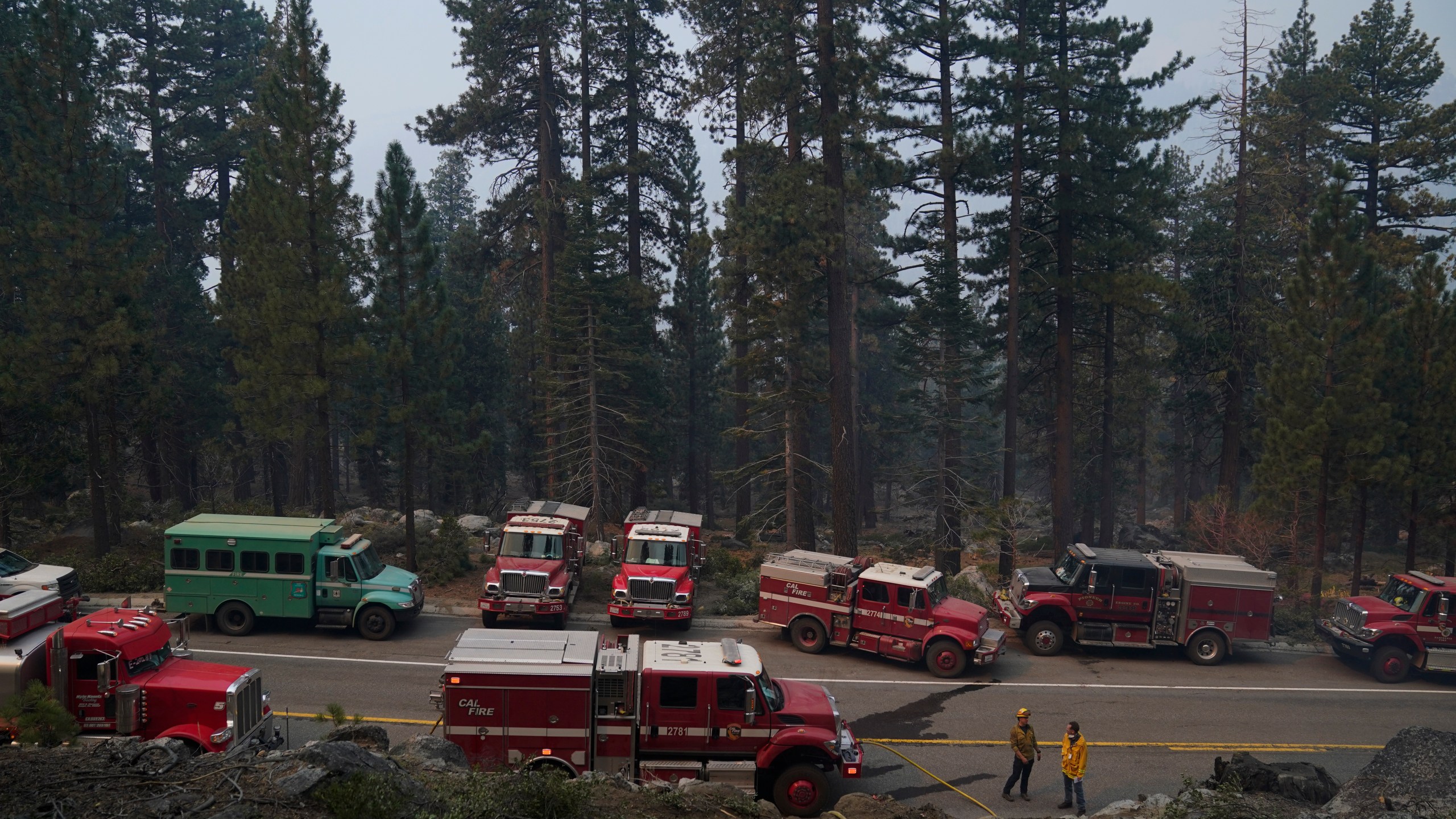 Fire trucks are parked along Highway 89 as fire crews build a fire line to keep the Caldor Fire from spreading in South Lake Tahoe, Calif., Friday, Sept. 3, 2021. Fire crews took advantage of decreasing winds to battle a California wildfire near popular Lake Tahoe and were even able to allow some people back to their homes but dry weather and a weekend warming trend meant the battle was far from over. (AP Photo/Jae C. Hong)