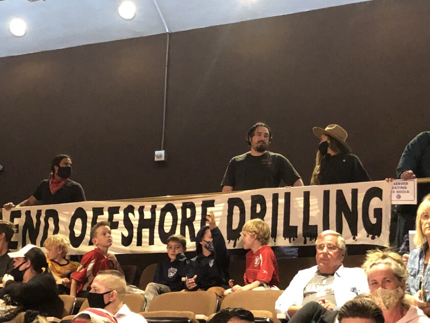 Members of the Surfrider Foundation hold a sign supporting an offshore oil drilling ban at a Huntington Beach City Council meeting on Oct. 19, 2021. (Matt Szabo / Daily Pilot)