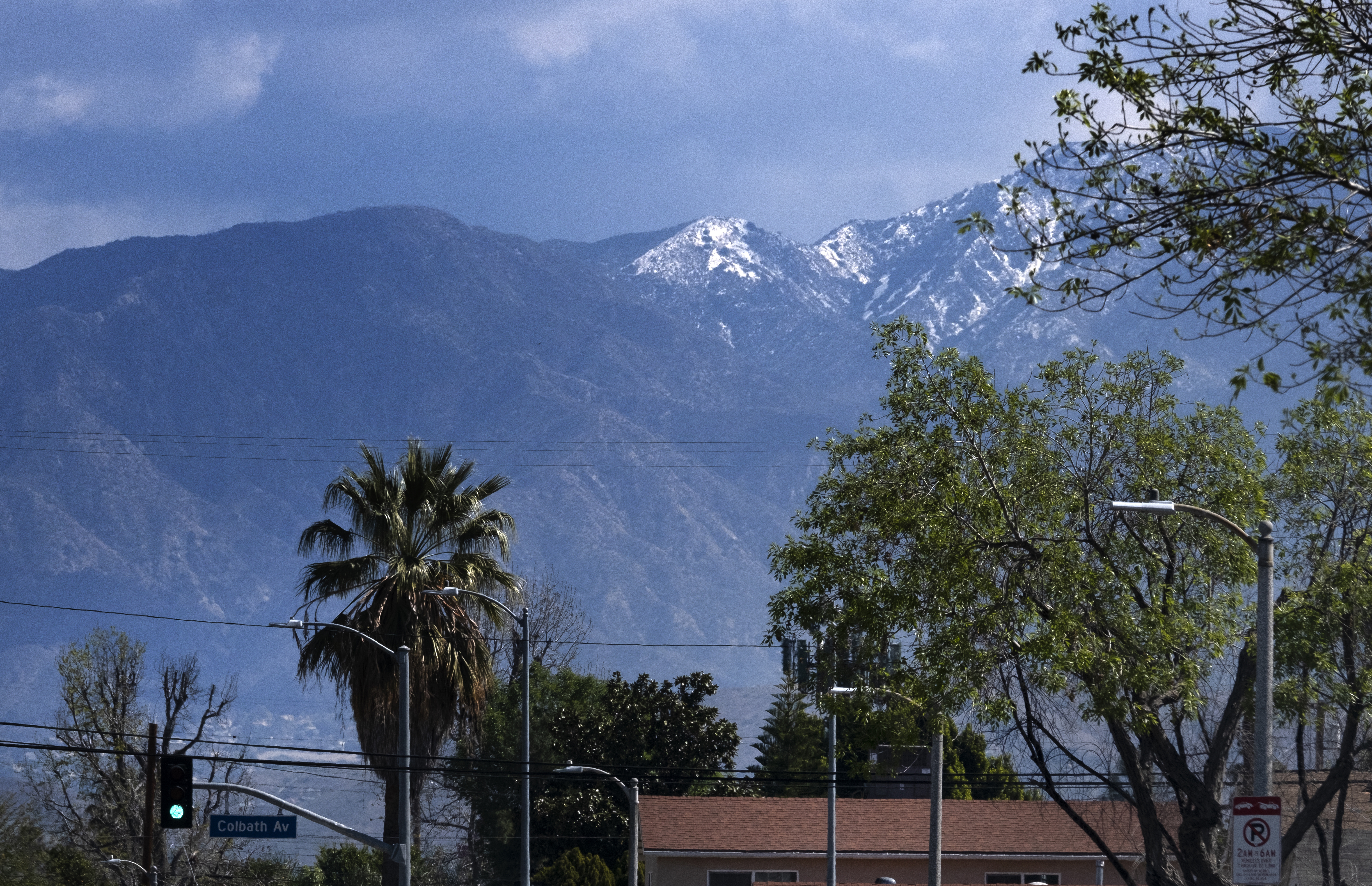 A lightly dusted snow capped hilltop is seen behind palm trees in the San Fernando Valley section of Los Angeles on March 12, 2021. (AP Photo/Richard Vogel)