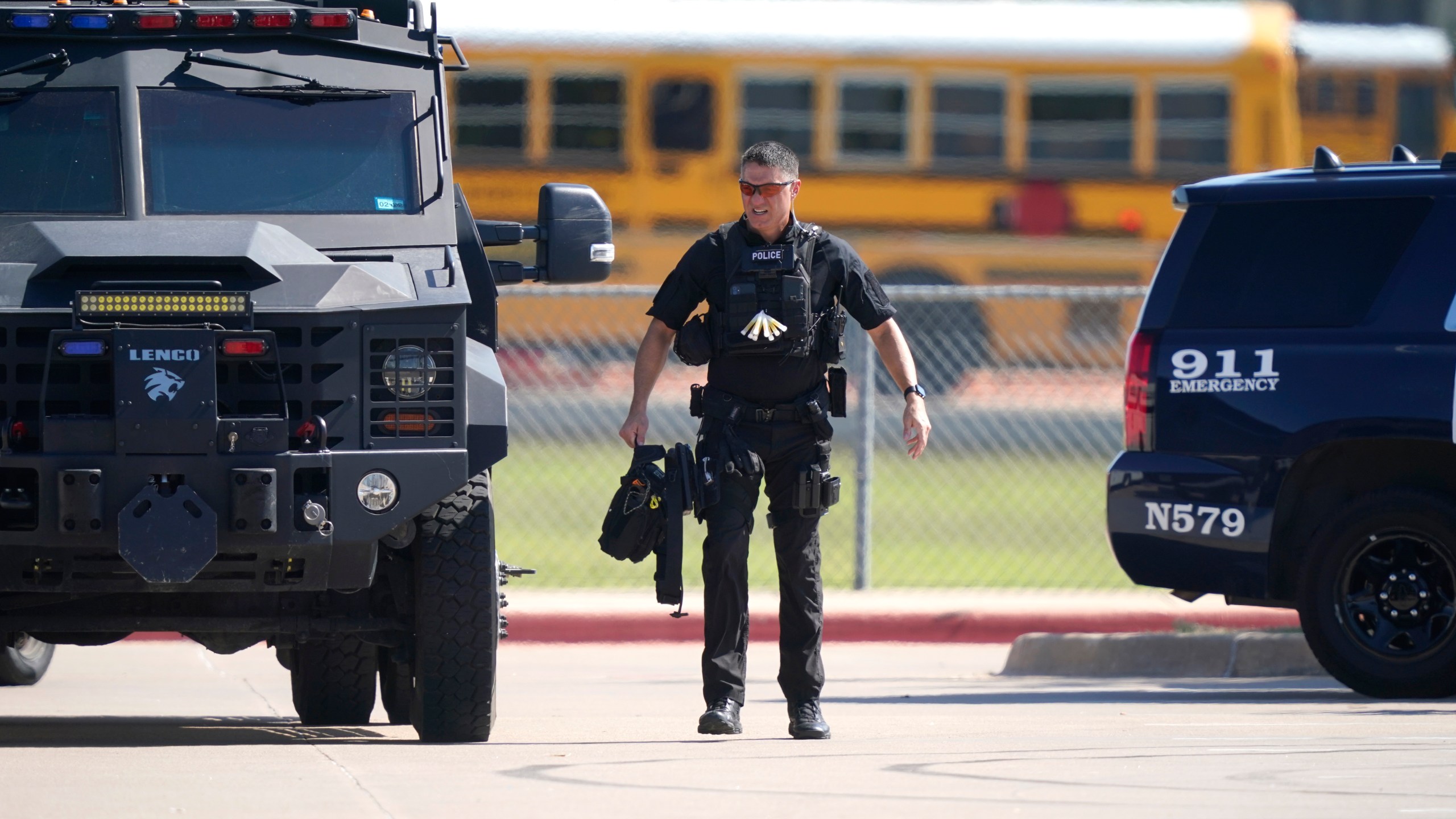 A law enforcement officer walks in the parking lot of Timberview High School after a shooting inside the school in south Arlington, Texas, Wednesday, Oct. 6, 2021. (AP Photo/LM Otero)