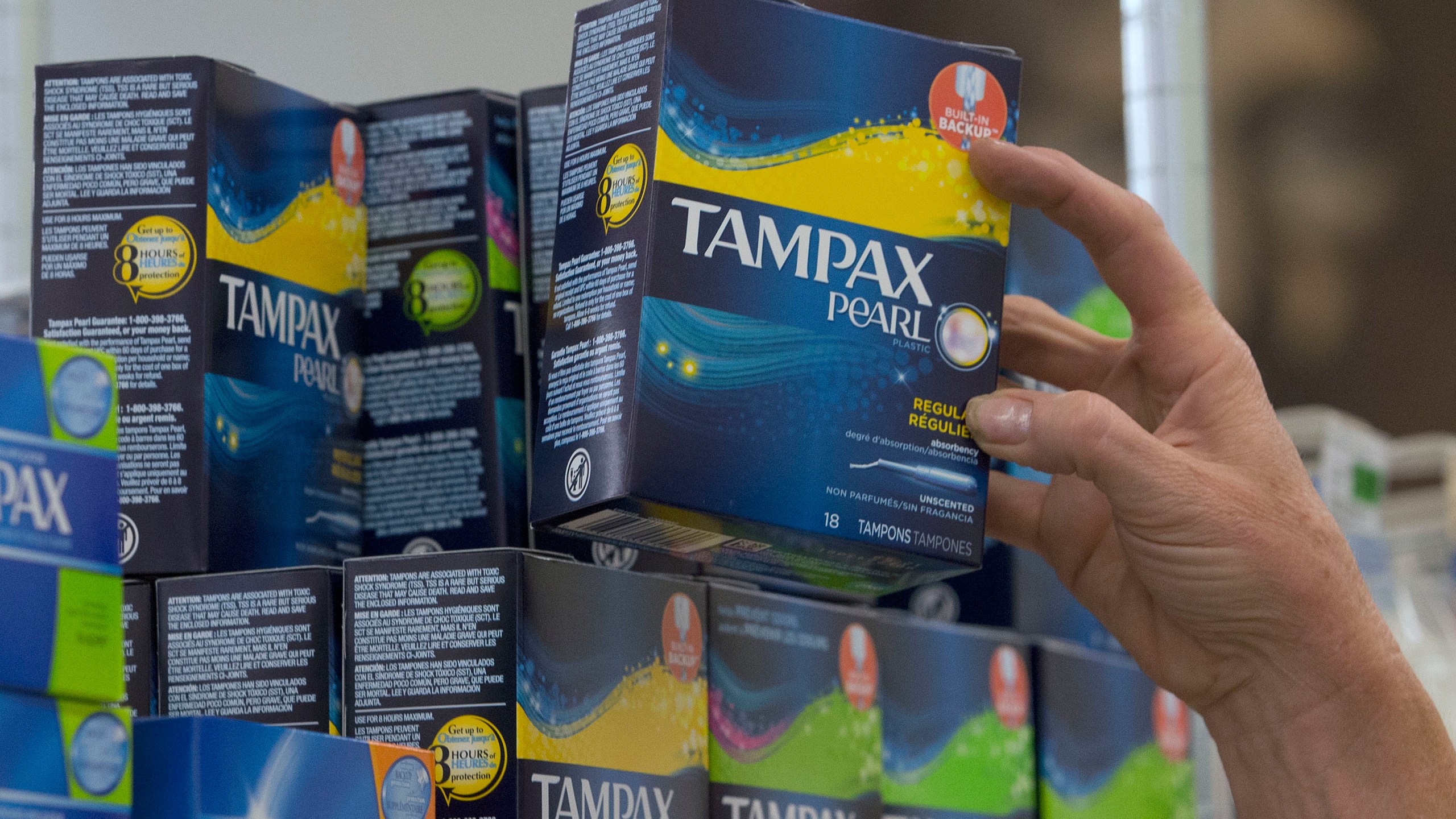 In this June 22, 2016 file photo, Tammy Compton restocks tampons at Compton's Market, in Sacramento, Calif. California public schools and colleges must stock their restrooms with free menstrual products under a new law signed by Gov. Gavin Newsom, Friday, Oct. 8, 2021. (AP Photo/Rich Pedroncelli, File)